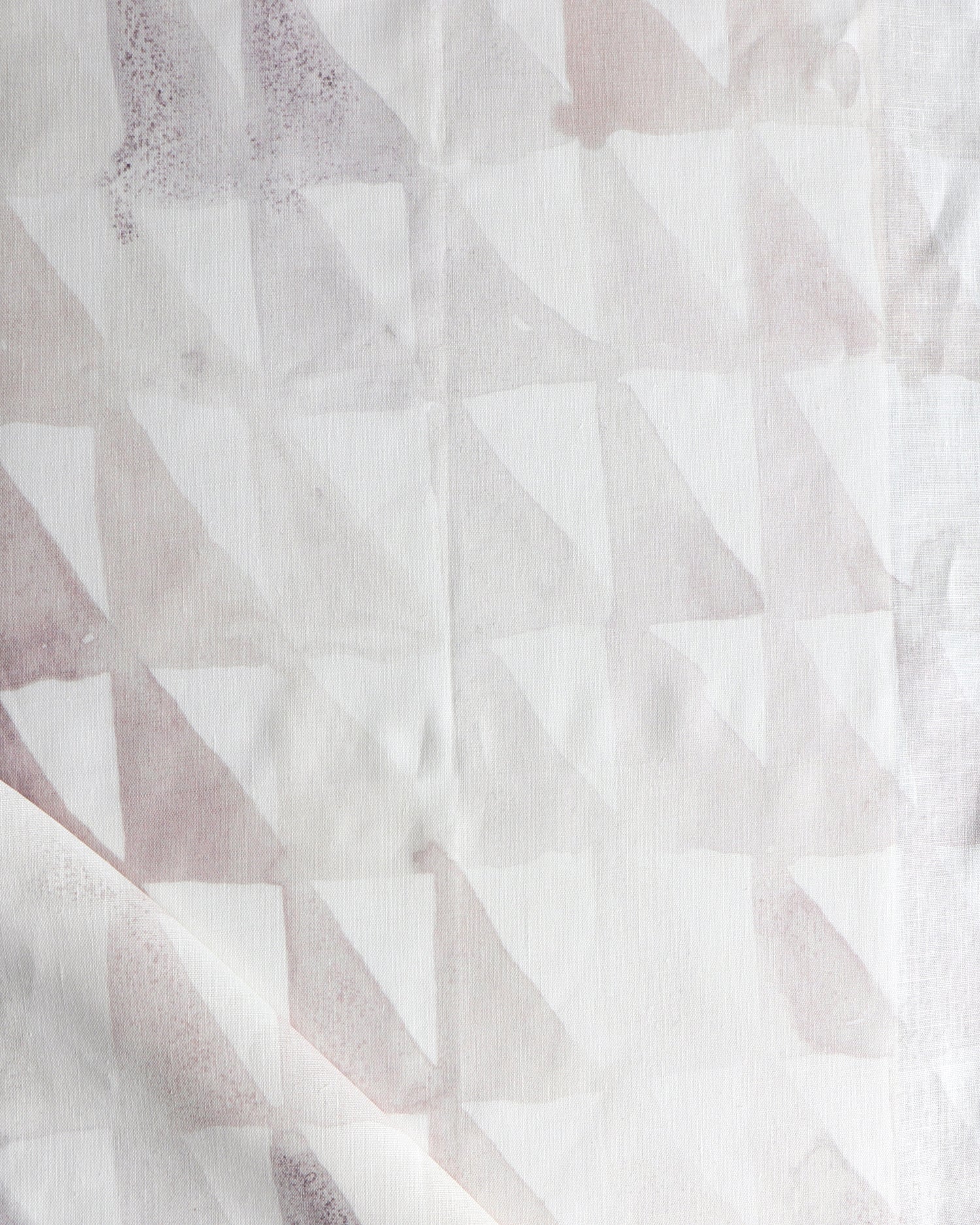 Detail of draped fabric in a painterly check pattern in shades of cream, tan and white.