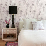 Bedroom with a white linened bed, side table and agaist a watercolor tree print in light grey and pink. 