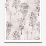 Wallpaper roll in a watercolor tree print in shades of light gray and pink on a cream field.