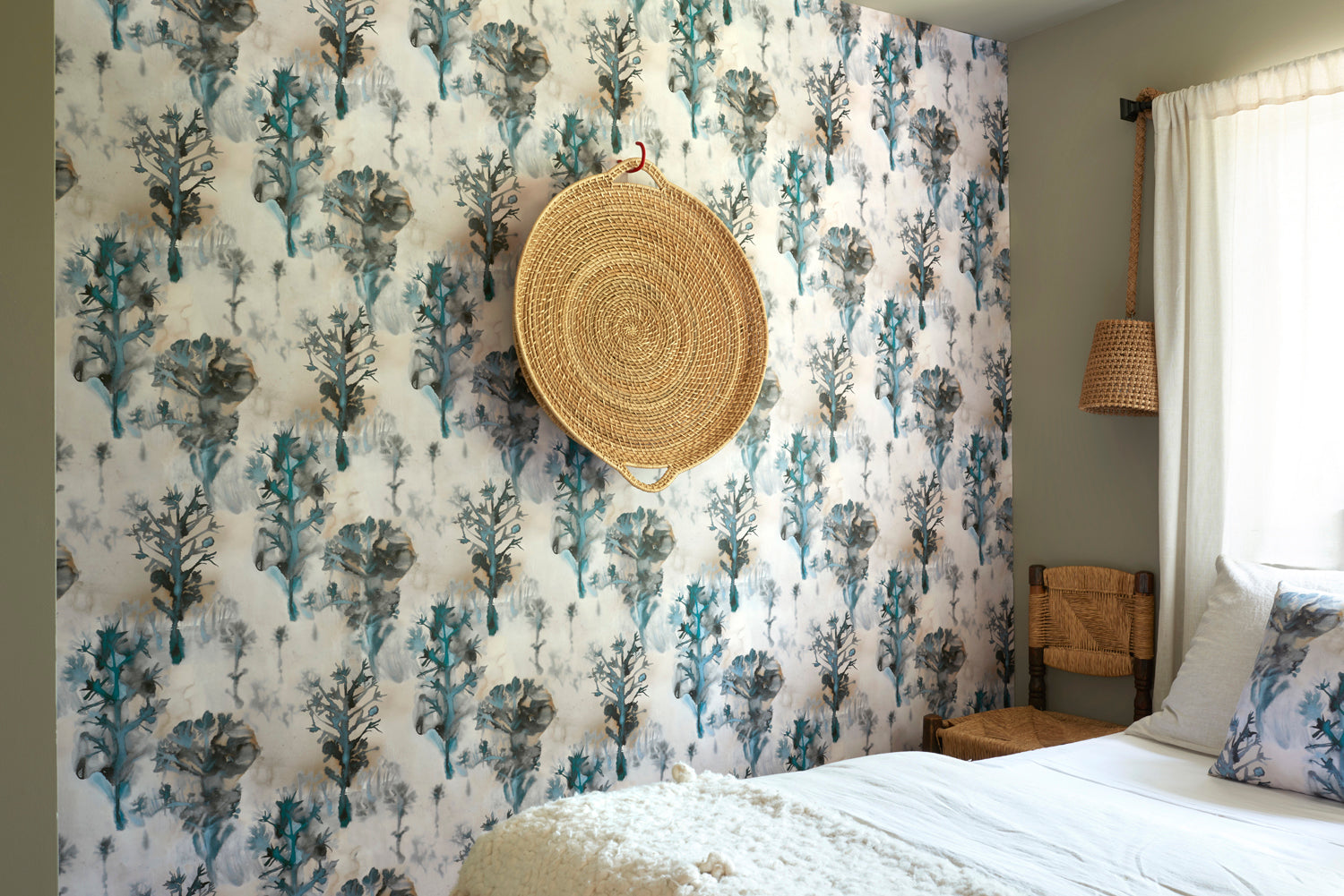 Bedroom scene against a watercolor tree print in shades of tan and gray on a blue field.