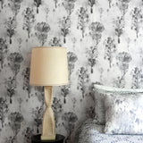 Bedroom scene against a watercolor tree print in shades of gray and black on a white field.