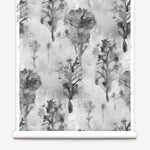 Wallpaper roll in a watercolor tree print in shades of gray and black on a white field.