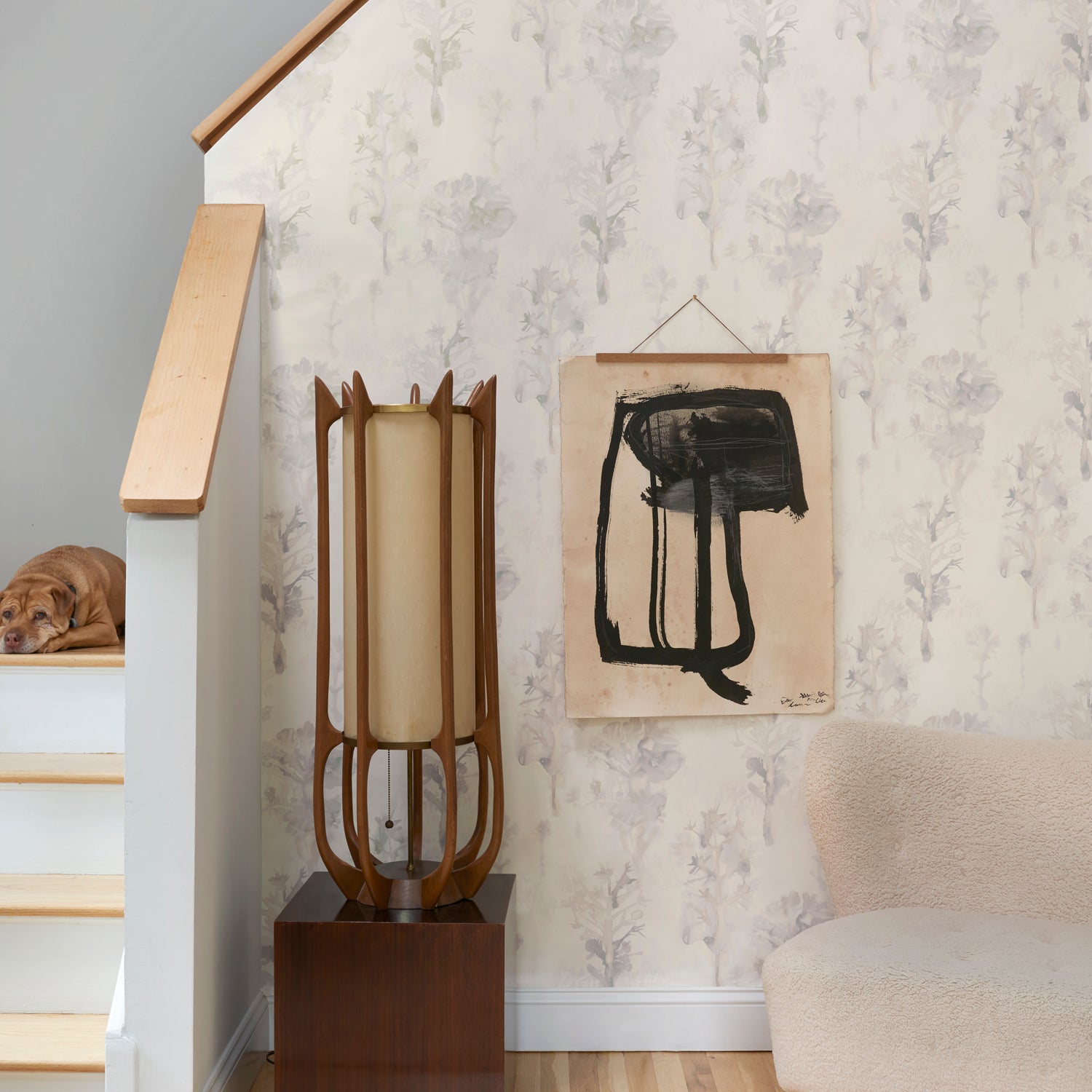 Staircase with wallpaper in watercolor tree print in shades of tan and gray on a white field.