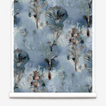 Wallpaper roll in a watercolor tree print in shades of gray and turquoise on a blue field.