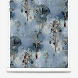 Wallpaper roll in a watercolor tree print in shades of gray and turquoise on a blue field.