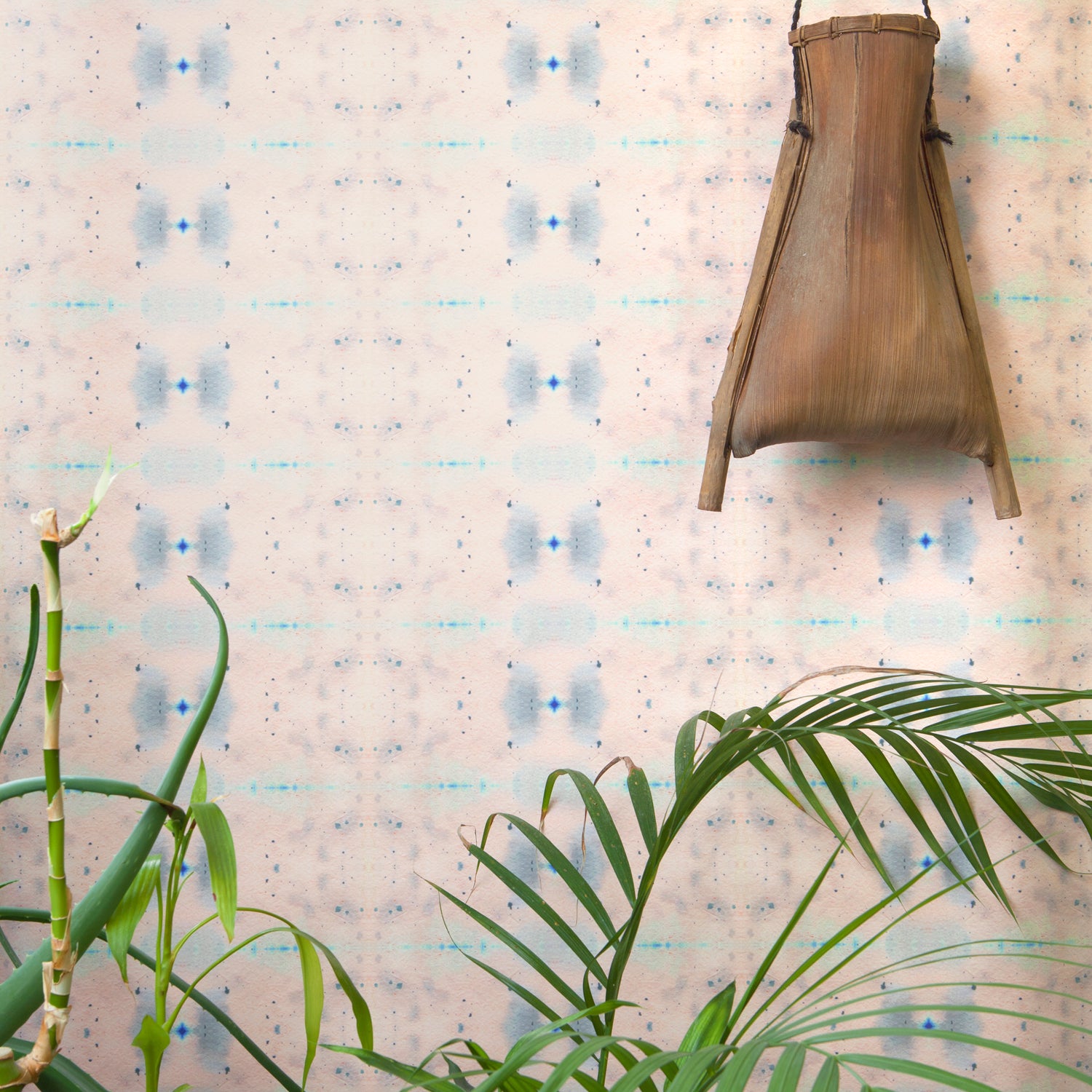 Wallpaper install in repeating ink blot print in shades of purple framed by a plant and hanging basket.