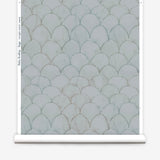 Wallpaper roll in a watercolor linear scallop pattern in green on a sage field. 