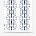 Wallpaper roll in a watercolor ikat stripe print in shades of blue and black on a white field.