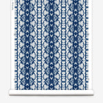 Wallpaper roll in a watercolor ikat stripe print in shades of white and blue on a gray field.