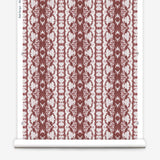 Wallpaper roll in a watercolor ikat stripe print in shades of white on a red field.