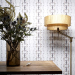 Wallpaper install in a watercolor ikat stripe print in shades of blue and black on a white field, with a floor lamp and wooden diting table. 