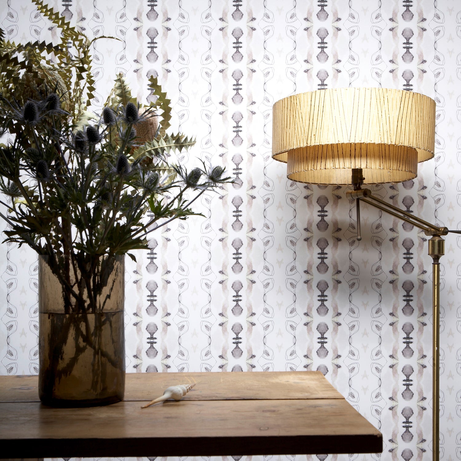 Wallpaper install in a watercolor ikat stripe print in shades of blue and black on a white field, with a floor lamp and wooden diting table. 