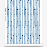Wallpaper roll in a painterly stripe print in blue on a white field.