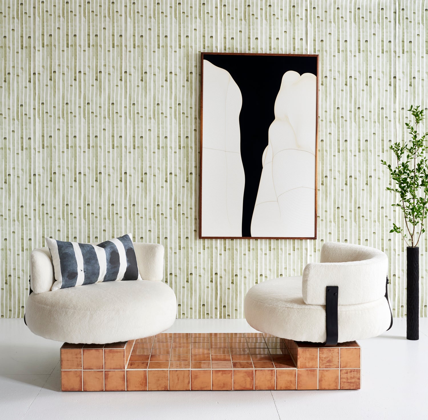 Wallpaper install a painterly stripe print in olive on a white field with white accent chairs, abstract painting, and a branch vase.