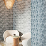 Dramatic tableau with white side chairs, sculptural pedestal table and glass pendant lamps surrounded by textural steel blue watercolor wallpaper. 