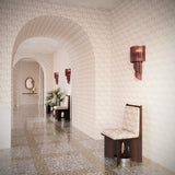 Arched hallway with terrazzo floors fully wallpapered in a texutral watercolor pattern in pastel pink. 