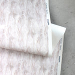 Draped Wallpaper roll in a layered squiggle watercolor pattern in shades of pastel pink. 