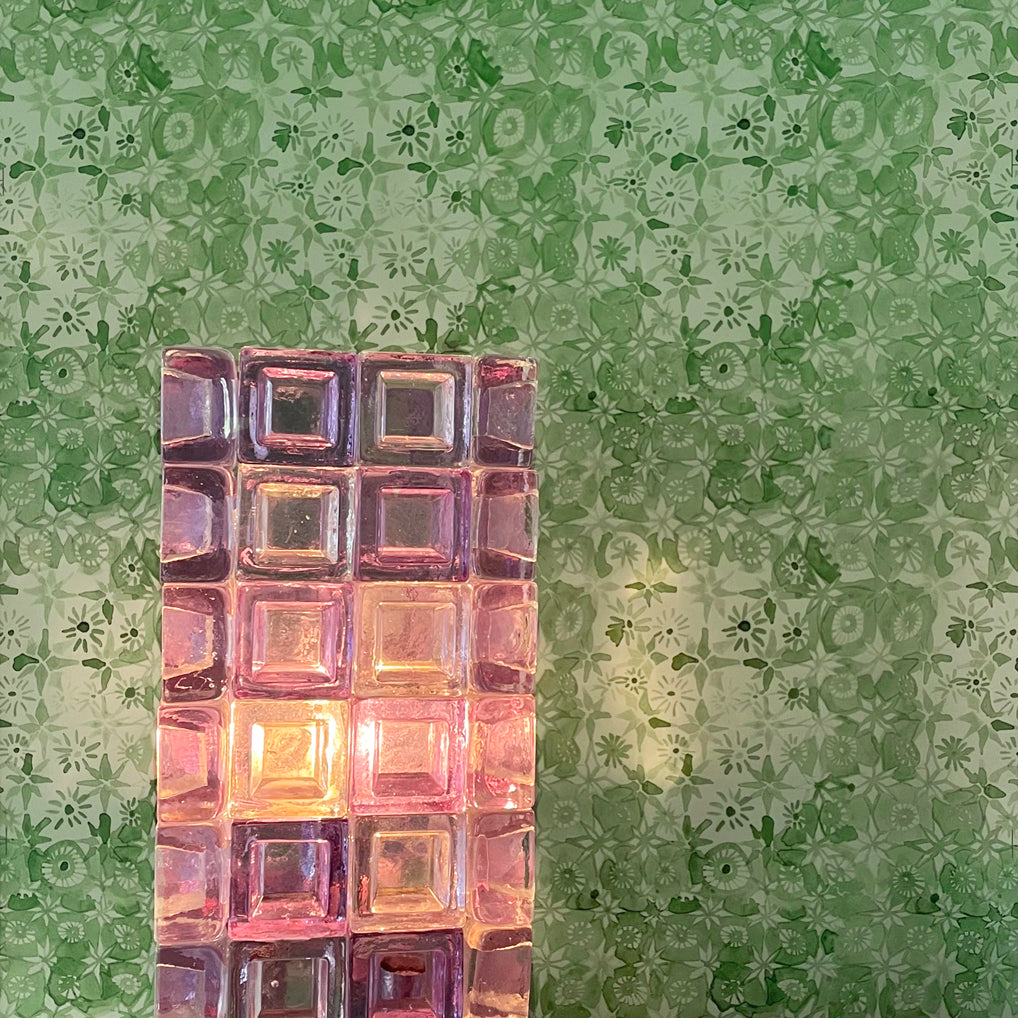 Decorative glass block light on a table with a patterned green wall in the background