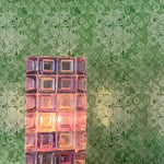 Decorative glass block light on a table with a patterned green wall in the background