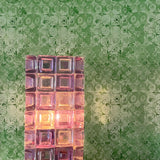 Decorative glass block light on a table with a patterned green wall in the background