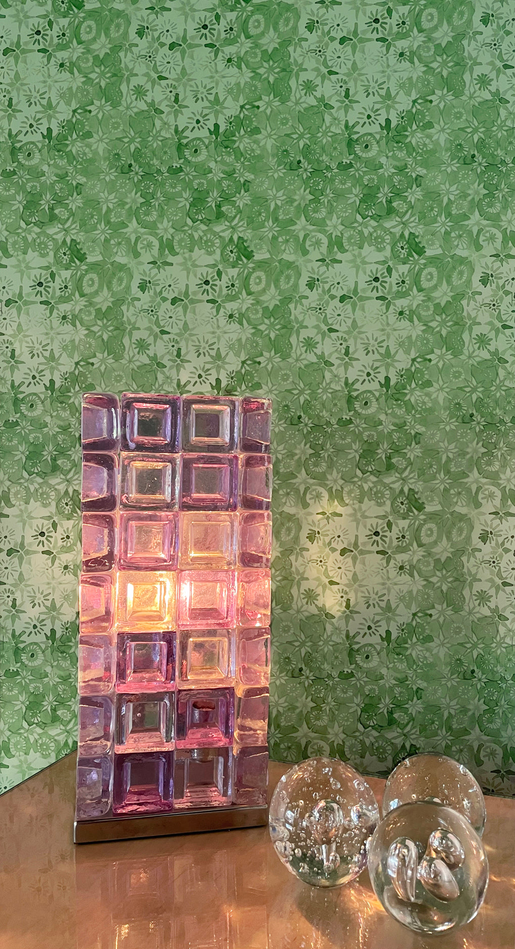 Decorative glass block light on a table with a patterned green wall in the background