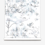 Wallpaper roll in a watercolor branch and floral pattern in shades of blue on a white field.