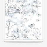 Wallpaper roll in a watercolor branch and floral pattern in shades of blue on a white field.