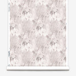 Wallpaper roll in a painterly tree print in light pink and purple on a cream field.
