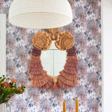 Dining room scene with ornate fringed mirror against painterly tree print wallpaper in turquoise, grey and coral. 
