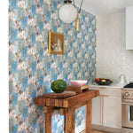 Kitchen scene with a wooden butcher block against wallpaper in a painterly tree print in gray and tan on a turquoise field.