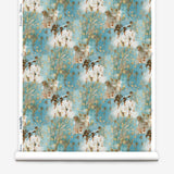 Wallpaper roll in a painterly tree print in gray and tan on a turquoise field.