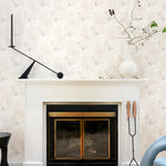 White fireplace hearth surrounded by in a painterly tree print in gray and tan, along side a chocolate lab. 