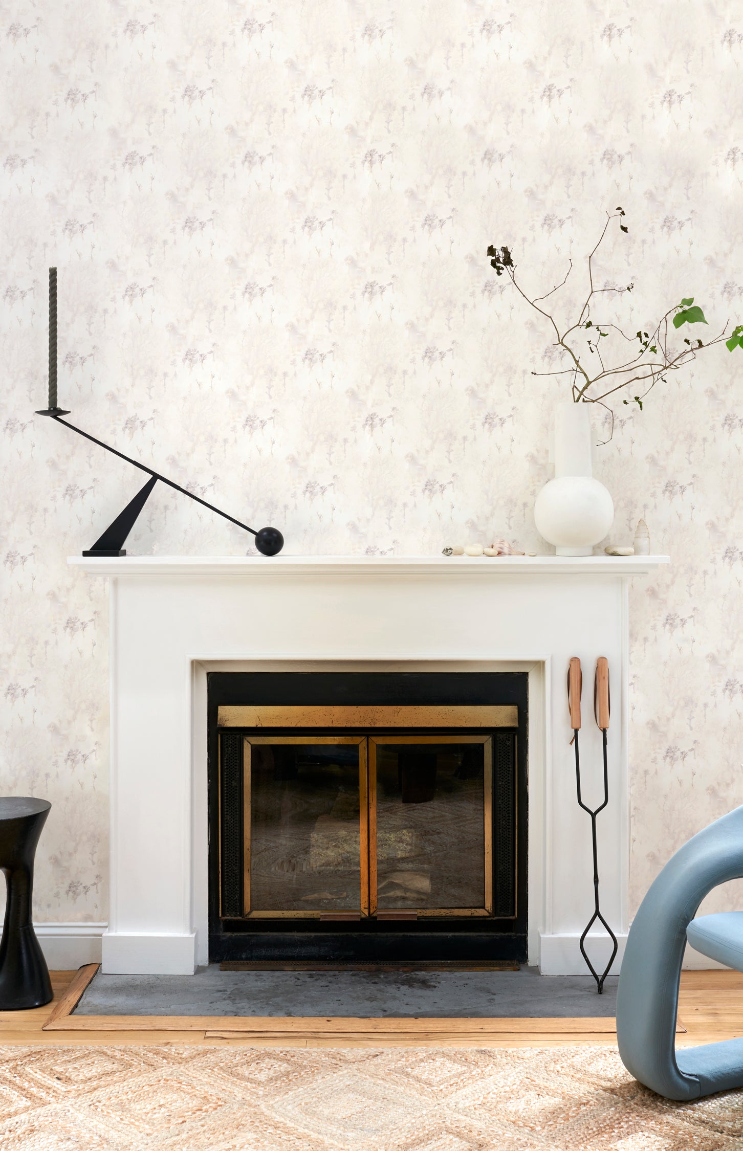 White fireplace hearth surrounded by in a painterly tree print in gray and tan, along side a chocolate lab. 