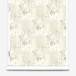Wallpaper roll in a painterly tree print in gray and tan on a white field.