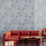 Retro orange leather couch against wallpaper in abstract floral bushstroke design in soft slate blue. 