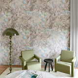 Living room wallpapered in painterly tree print in cream, gray and turquoise with green side chairs, accent lamp and marble coffee table. 