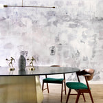 Dining room table and chairs against wallpaper mural in a minimal splatter print in shades of gray on a cream field.