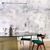 Dining room table and chairs against wallpaper mural in a minimal splatter print in shades of gray on a cream field.
