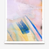 Wallpaper roll in an ombré watercolor print in shades of pink, purple and blue on a cream field.