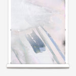 Wallpaper roll in an ombré watercolor print in shades of pink, gray and purple on a cream field.