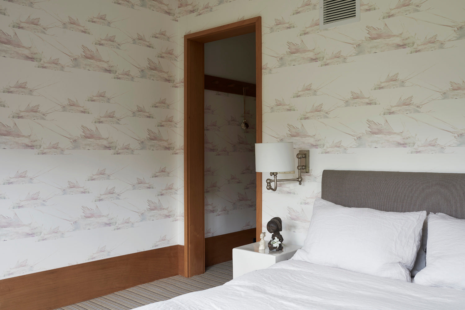 Bedroom scene wallpapered in a watercolor splatter print in pastel purple and gray on a cream field.