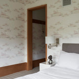 Bedroom scene wallpapered in a watercolor splatter print in pastel purple and gray on a cream field.