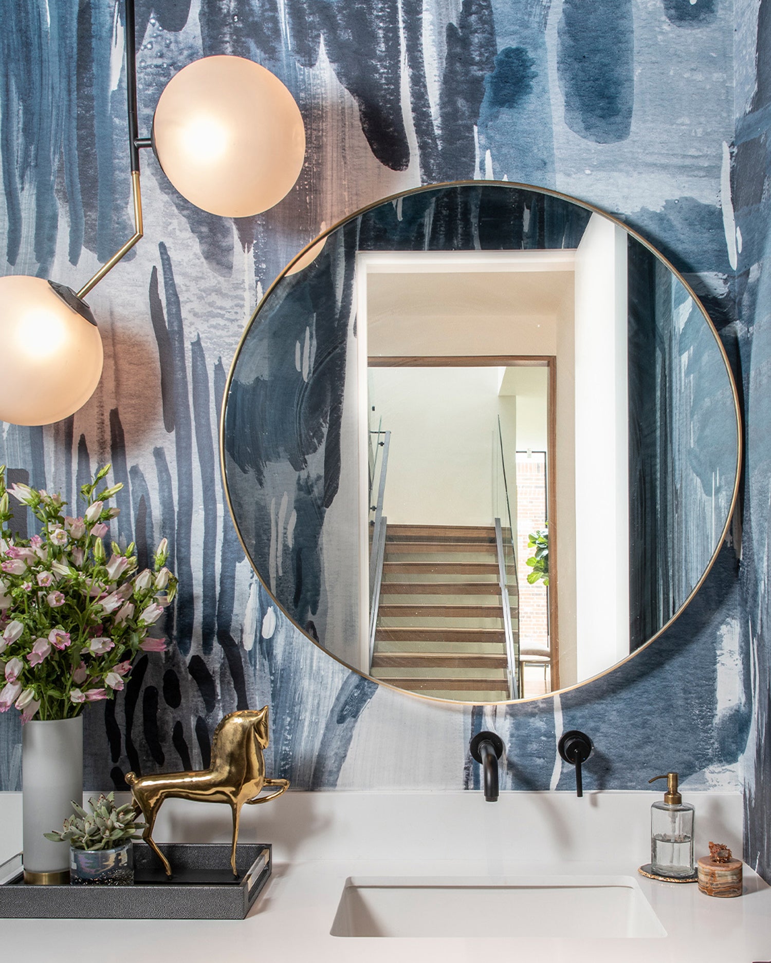 Powder room sink and mirroy aginsta a watercolor mural in dark blue. 