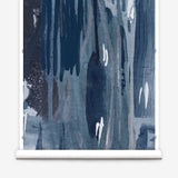 Wallpaper mural roll in a watercolor paint print in shades of black, purple and blue on a gray field.