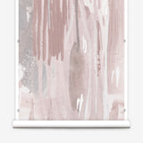 Wallpaper mural roll in a watercolor paint print in shades of pink, brown and gray on a cream field.