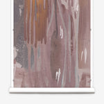 Wallpaper mural roll in a watercolor paint print in shades of gray, orange and purple on a cream field.