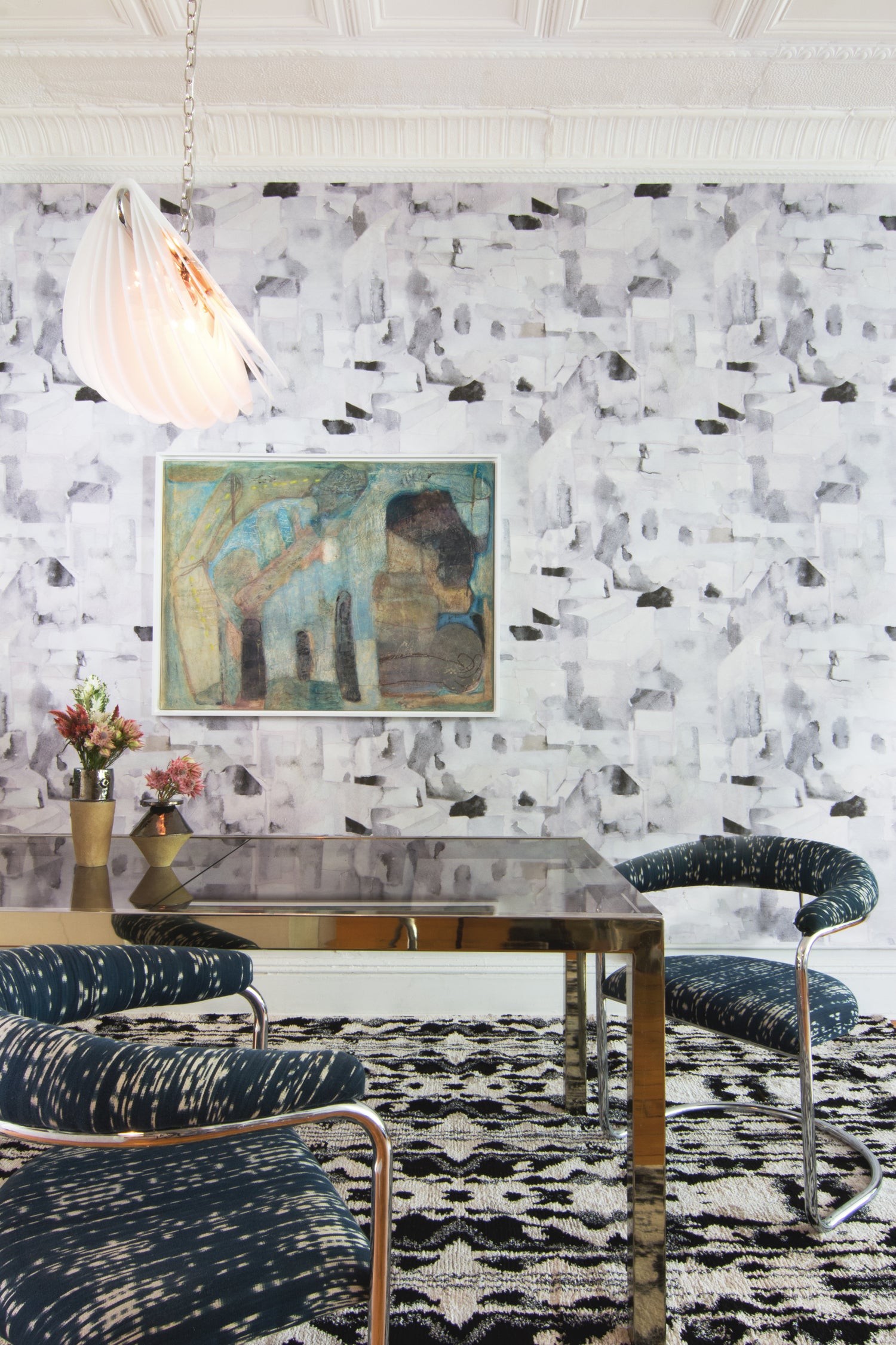 Dining room with modern furniture against wallpaper in a textural paint blotch print in shades of gray and blue on a light gray field.