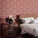 Bedroom scene with wooden furniture against a wallper in an undulating abstract watercolor motif in pink, orange and grey. 