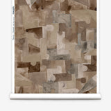 Wallpaper roll in a geometric puzzle piece watercolor pattern in brown and charcoal. 