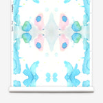 Wallpaper roll in a watercolor ink splash print in shades of blue and green on a cream field.